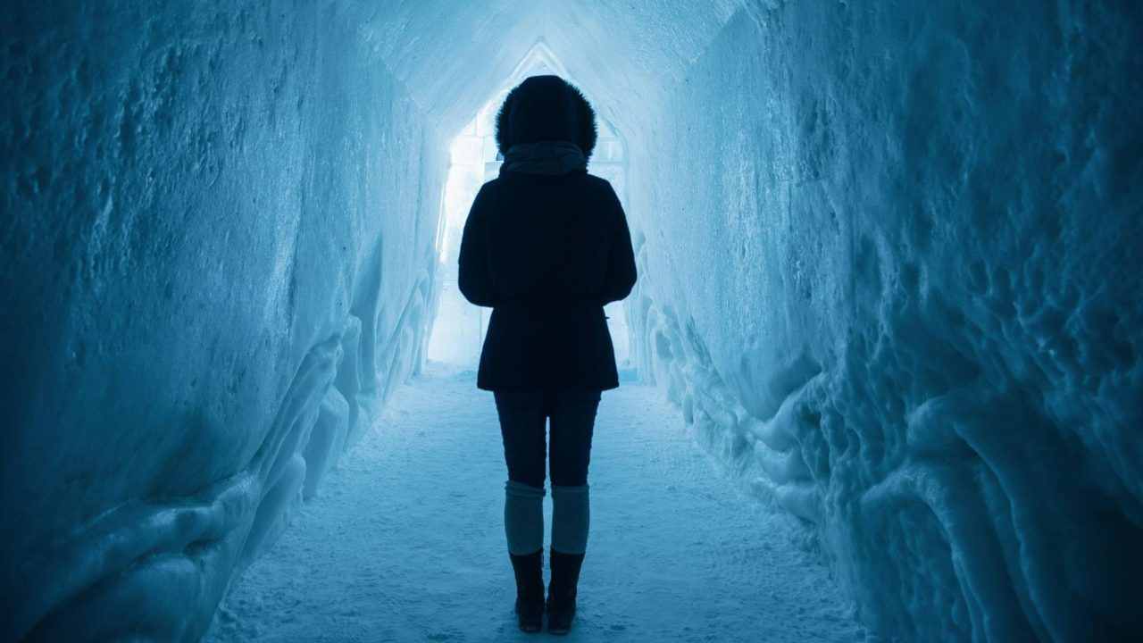 Egy nő sétál át egy jég alagúton.
