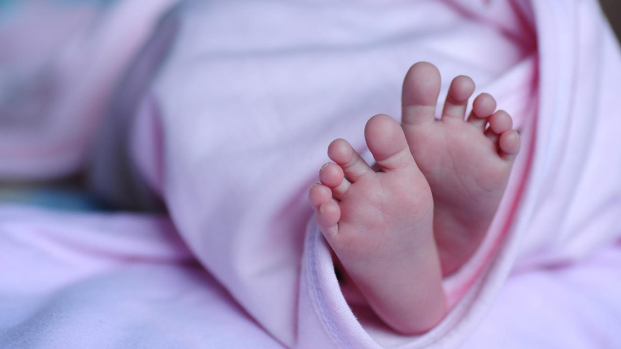 Csecsemő lábak bukkannak elő egy rózsaszín takaróból.