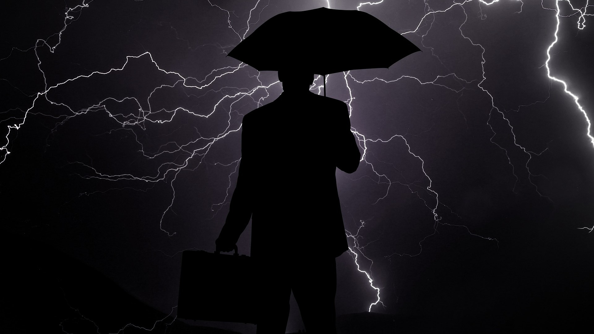 Üzletember az viharban egy esernyővel.