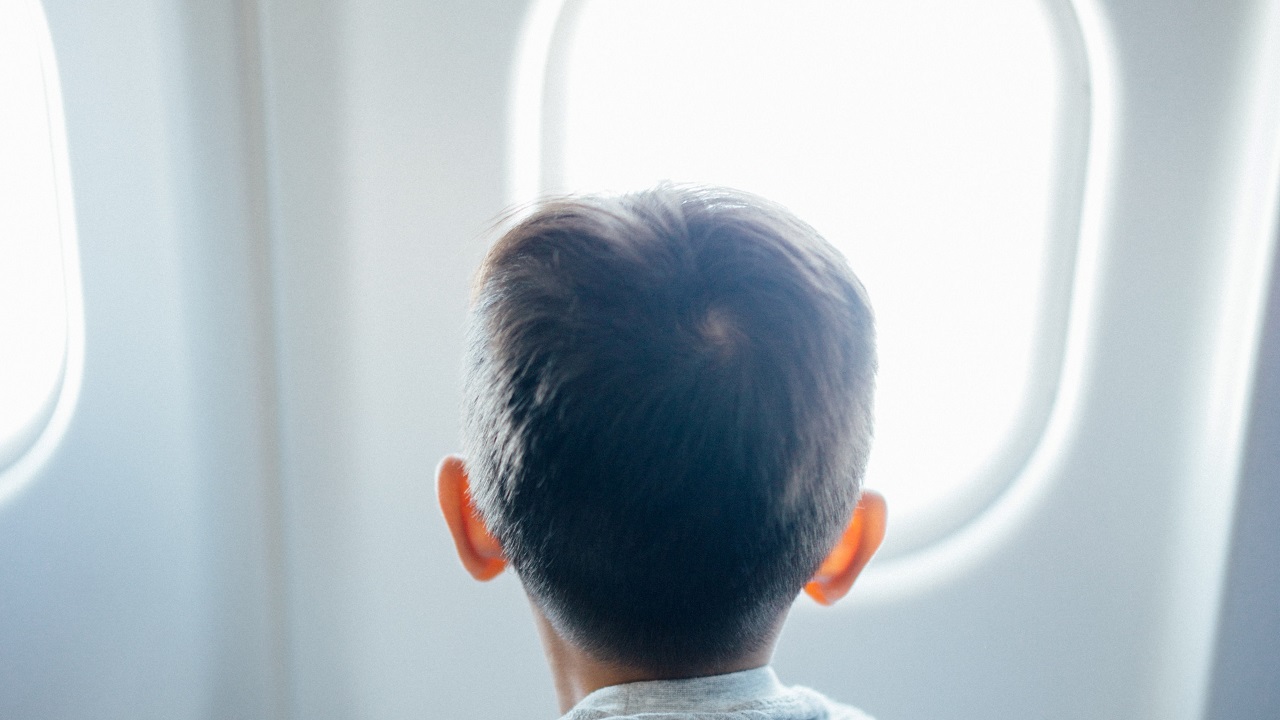 gyerek néz ki a repülő ablakán