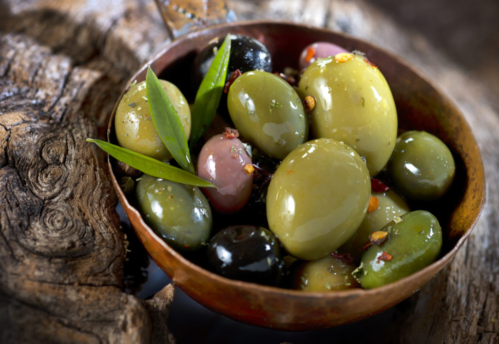 Különböző fajtájú olívabogyók, olívolaj és olajfalevelek 