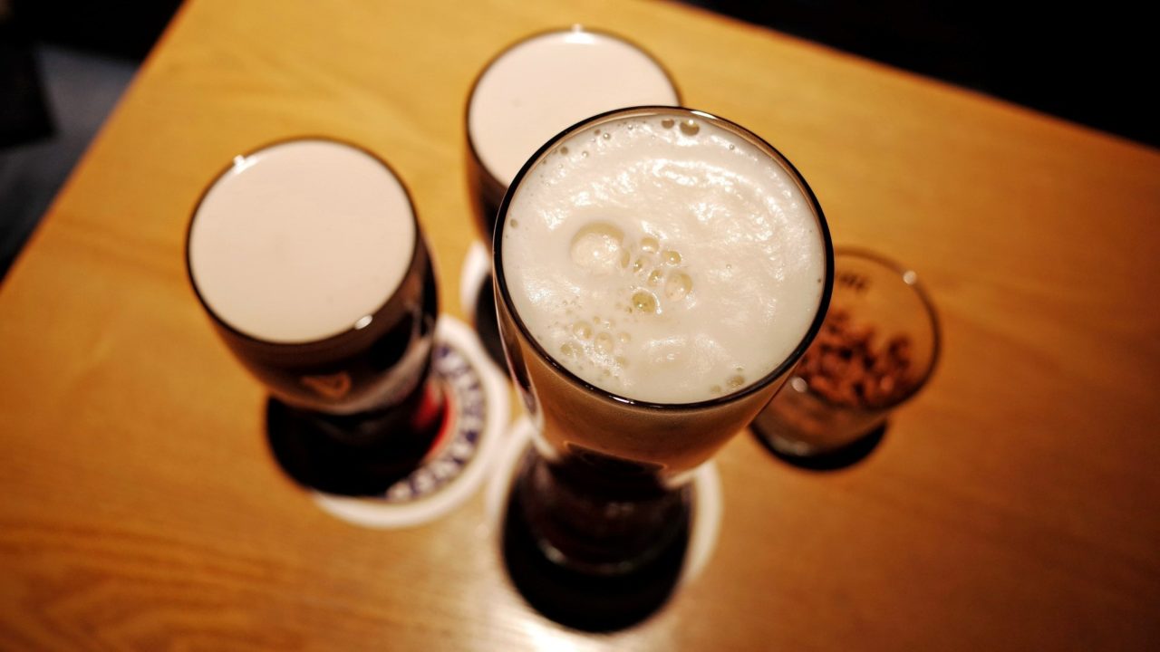Három pohár sör egymás mellett egy asztalon és valami rövid ital felülről.