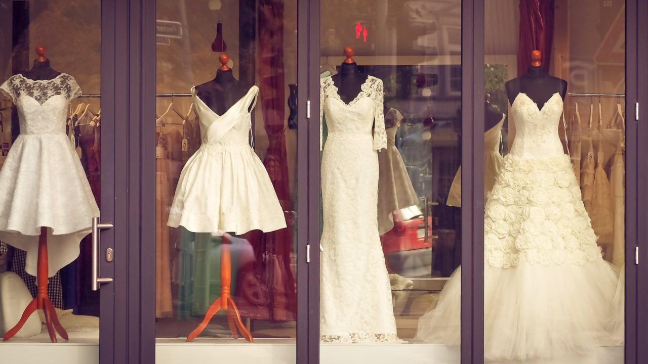 Különböző esküvői ruhák egy kirakatban egymás mellett.