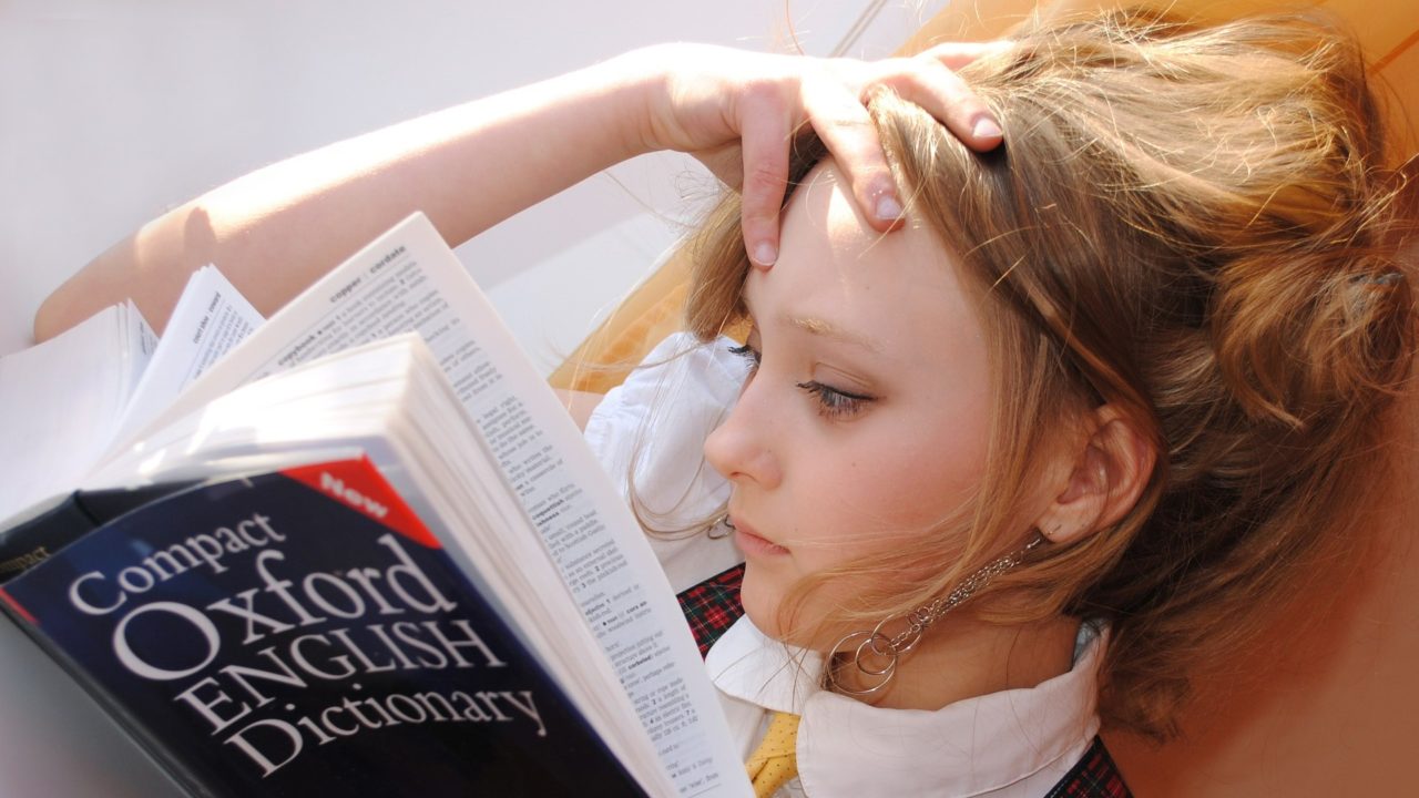 Fiatal nő olvassa az Oxford English Dictionary-t.