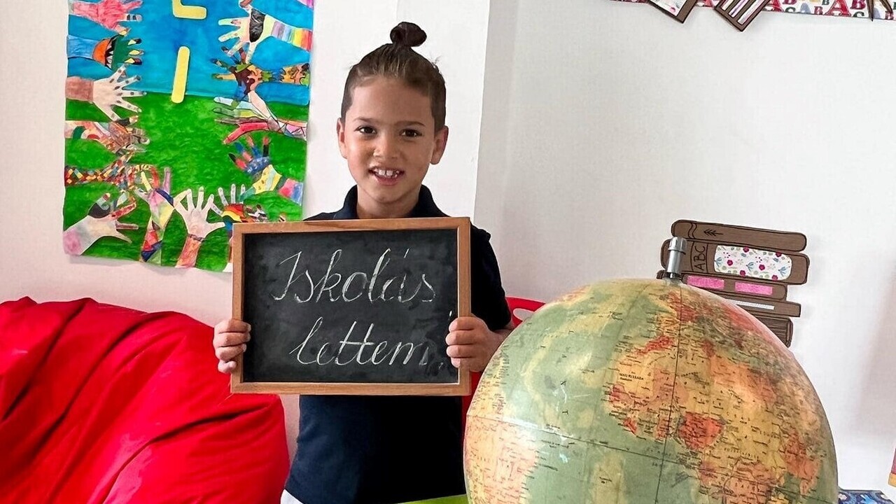 Majka kisfia Olivér egy táblával, amin az áll, hogy "Iskolás lettem".