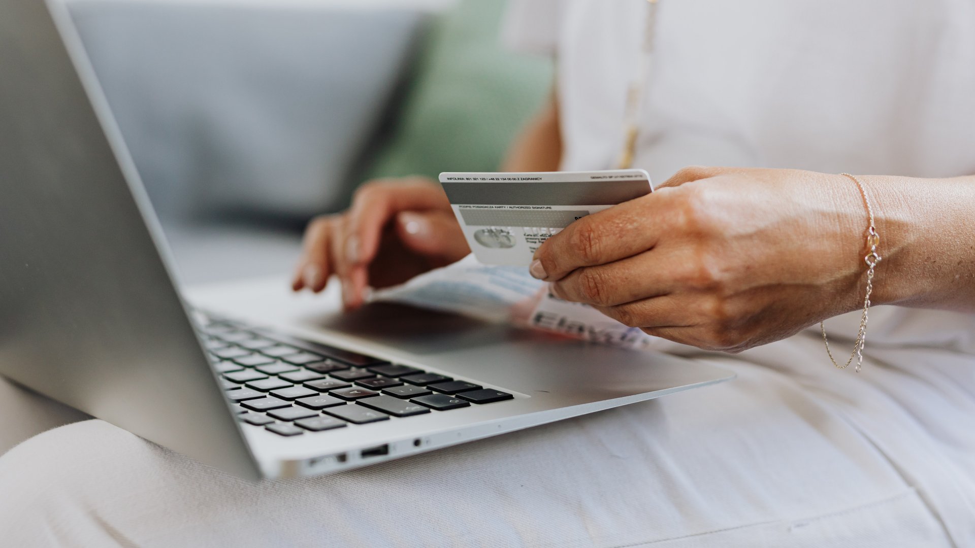 Egy nő a bankkártya adatait adja meg az online vásárlás során a laptopon