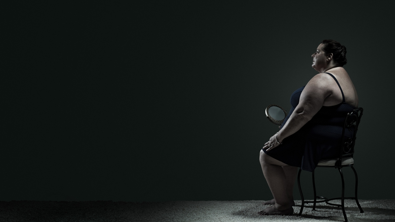 Kövér nő ül a széken a sötétben