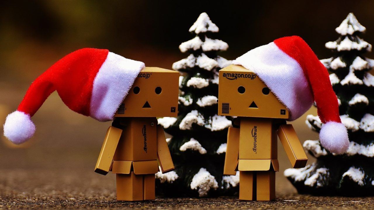 Dobozokból összeállított két télapó sapkás figura két mini karácsonyfa előtt.