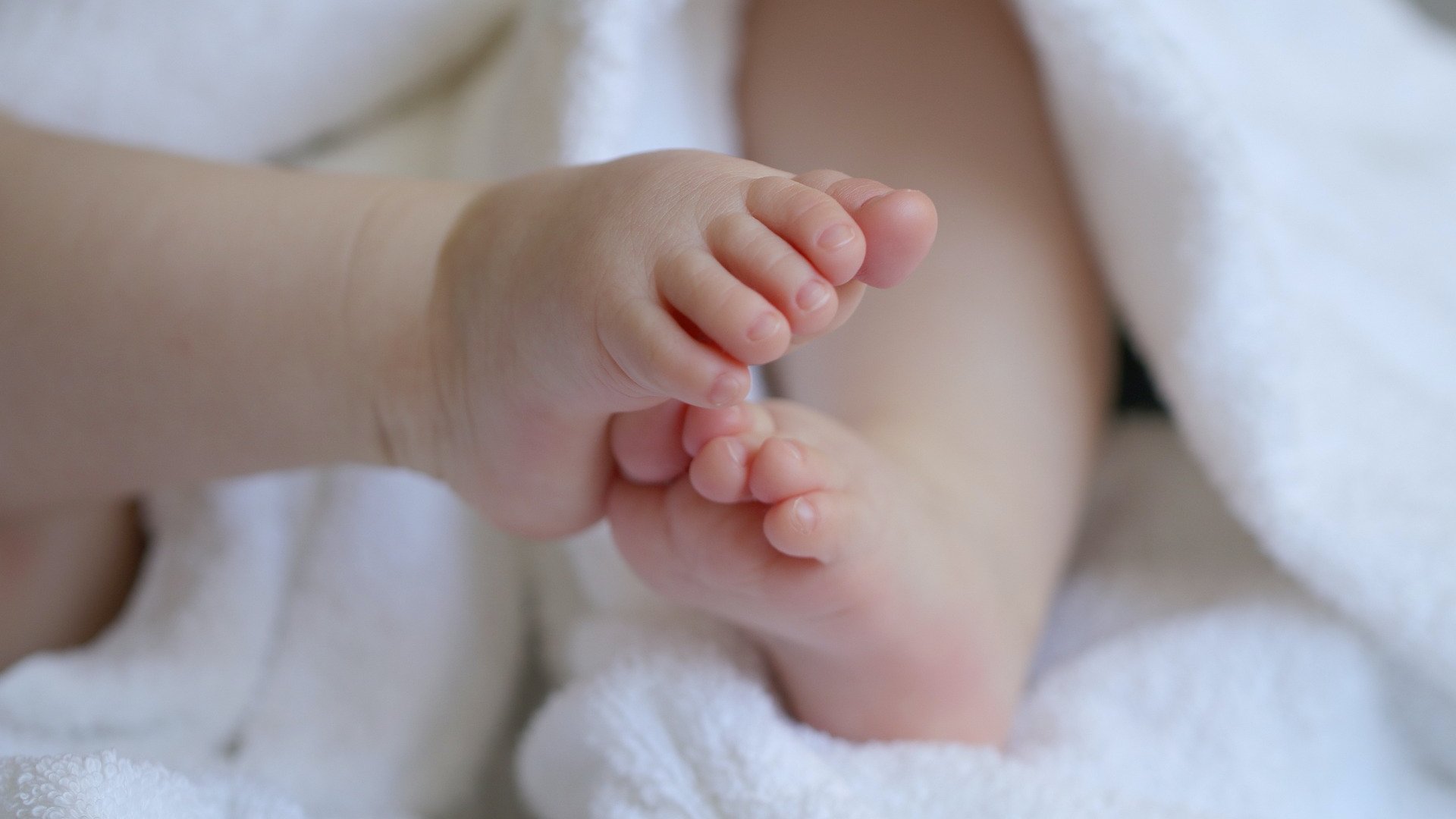 Egy kisbaba lábai a takaróból kikandikálva