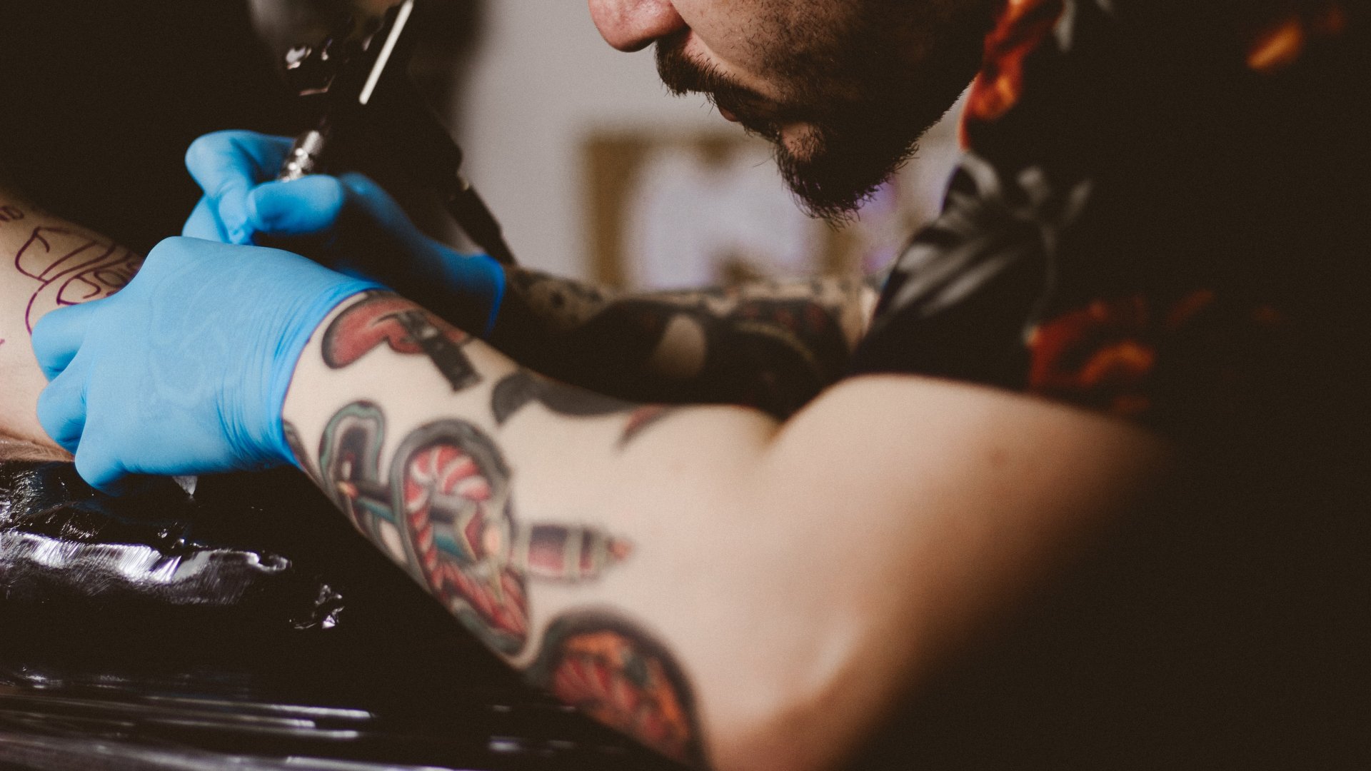 Tetoválást készít gumikesztyűben egy tetoválóművész