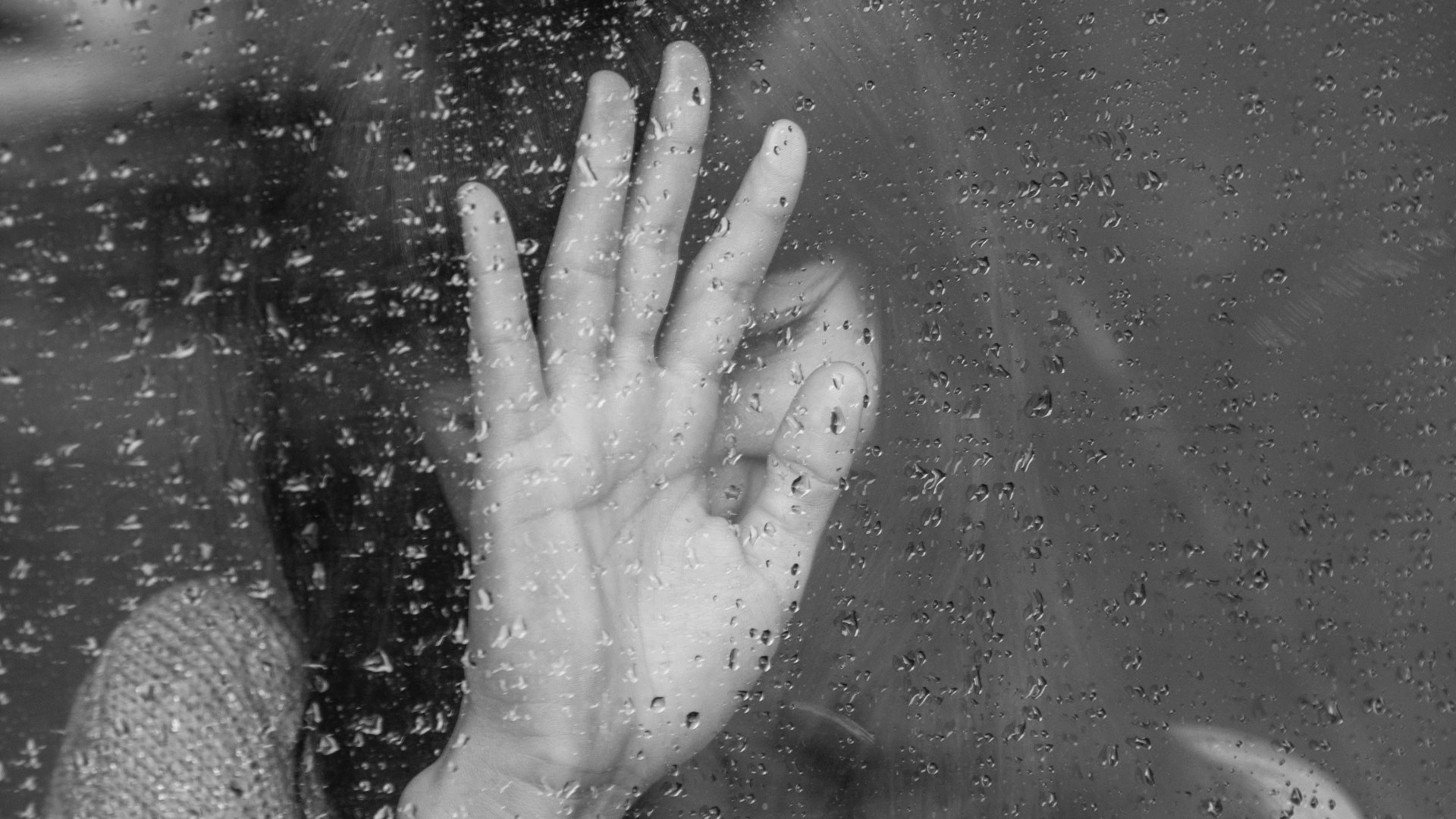 Arcát eltakaró lány az esős ablak előtt