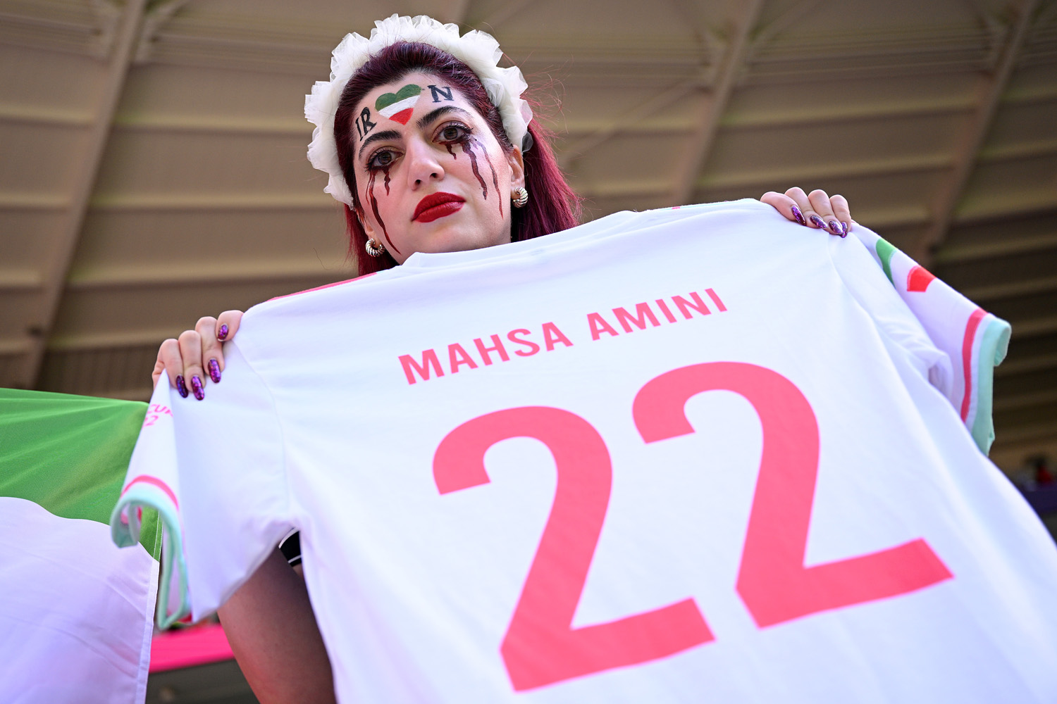 Egy iráni szurkoló Mahsa Amini nevével ellátott mezzel tüntet a női jogokért, a Wales-Irán mérkőzésen, 2022. november 25-én (Mahsa Amini volt az a nő, akit letartóztattak Teheránban hiányos öltözete miatt, majd a rendőrök később halálra verték) - Fotó: Matthias Hangst/Getty Images