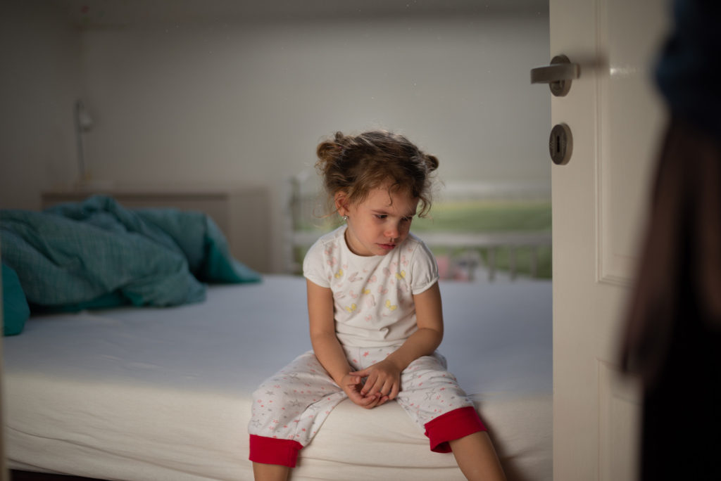 Kislány ül az ágy szélén a büntetés után
