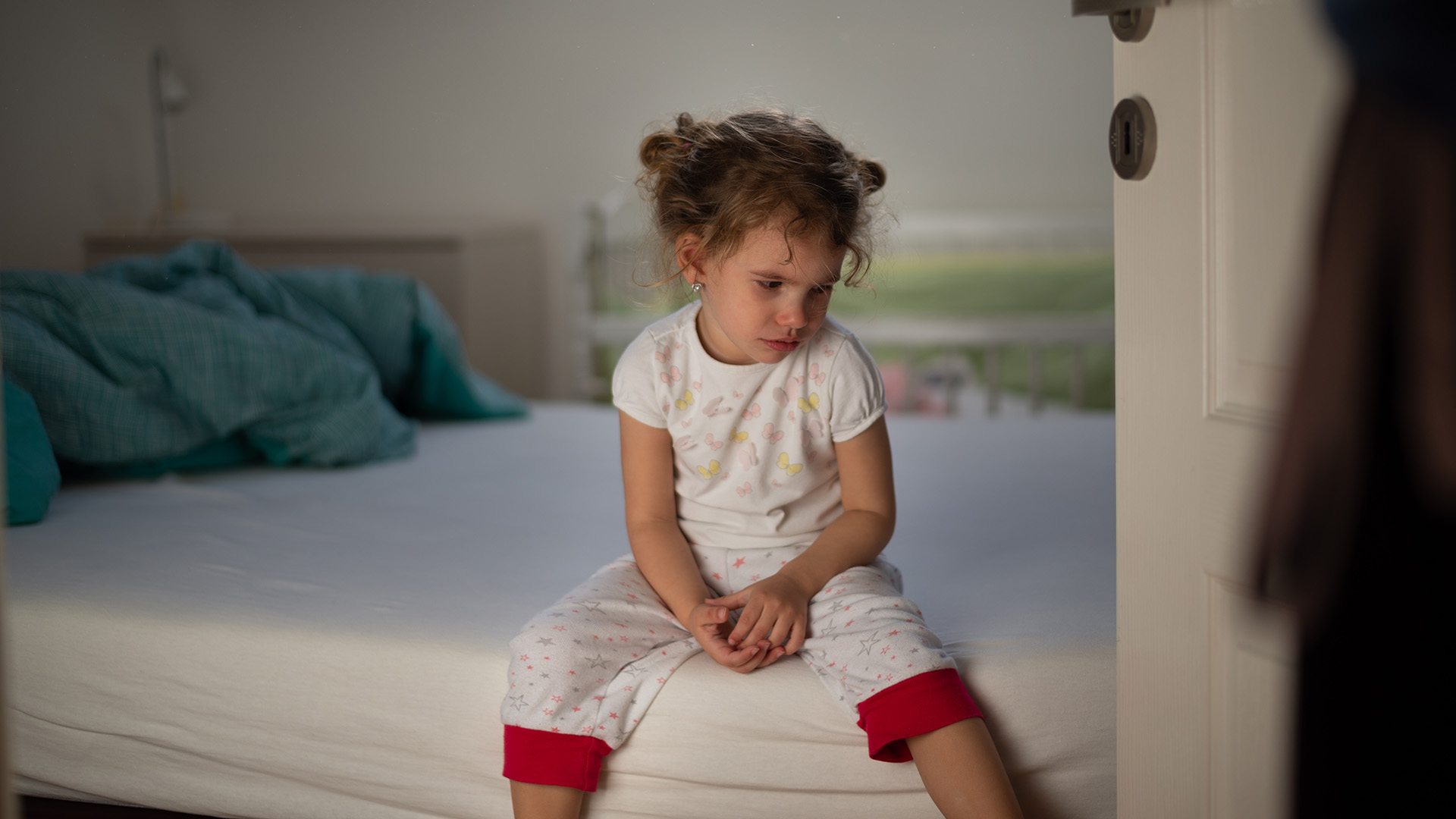 Kislány ül az ágy szélén a büntetés után