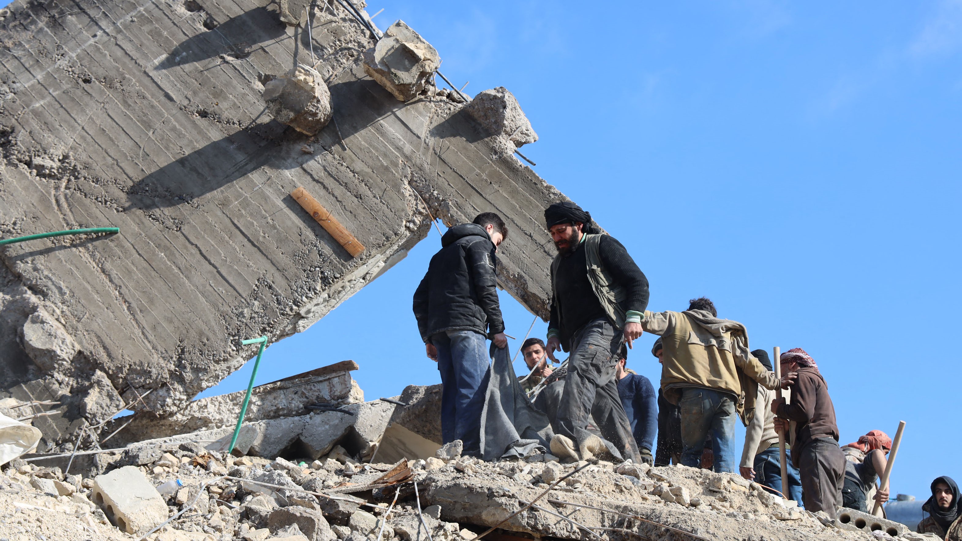 Emberek gyülekeznek egy összedőlt épület romjai fölött 2023. február 7-én Dzsandarisz városában