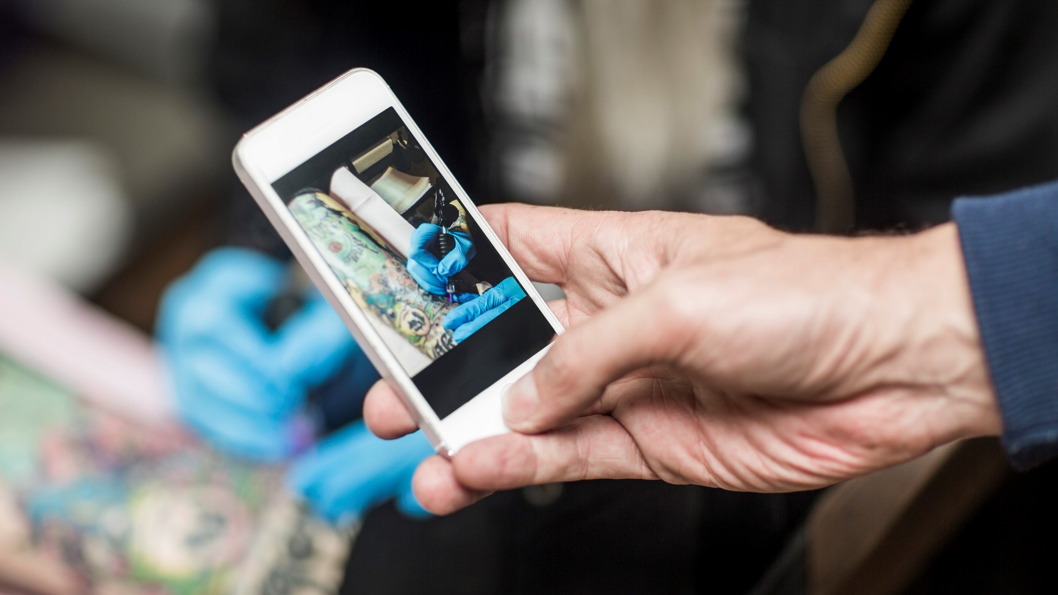 Telefonnal fotóz egy férfi egy tetoválót munka közben