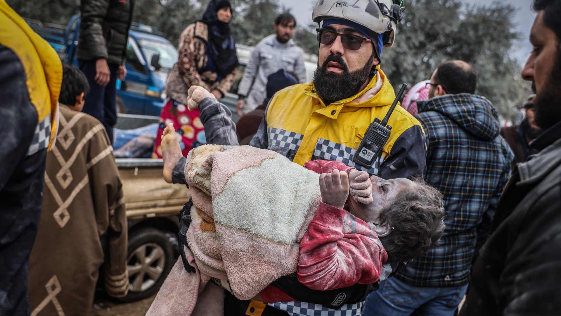 Mentős visz egy, a romok alól mentett gyereket Szíriában