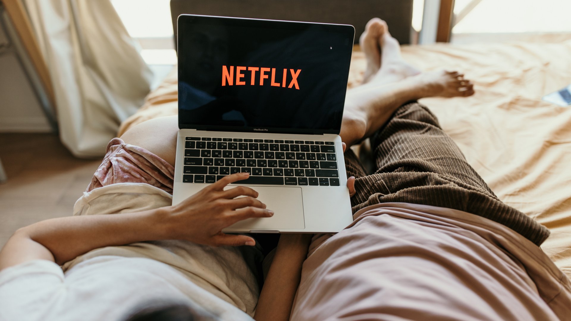Ágyban fekvő pár Netflixet néz egy laptopon