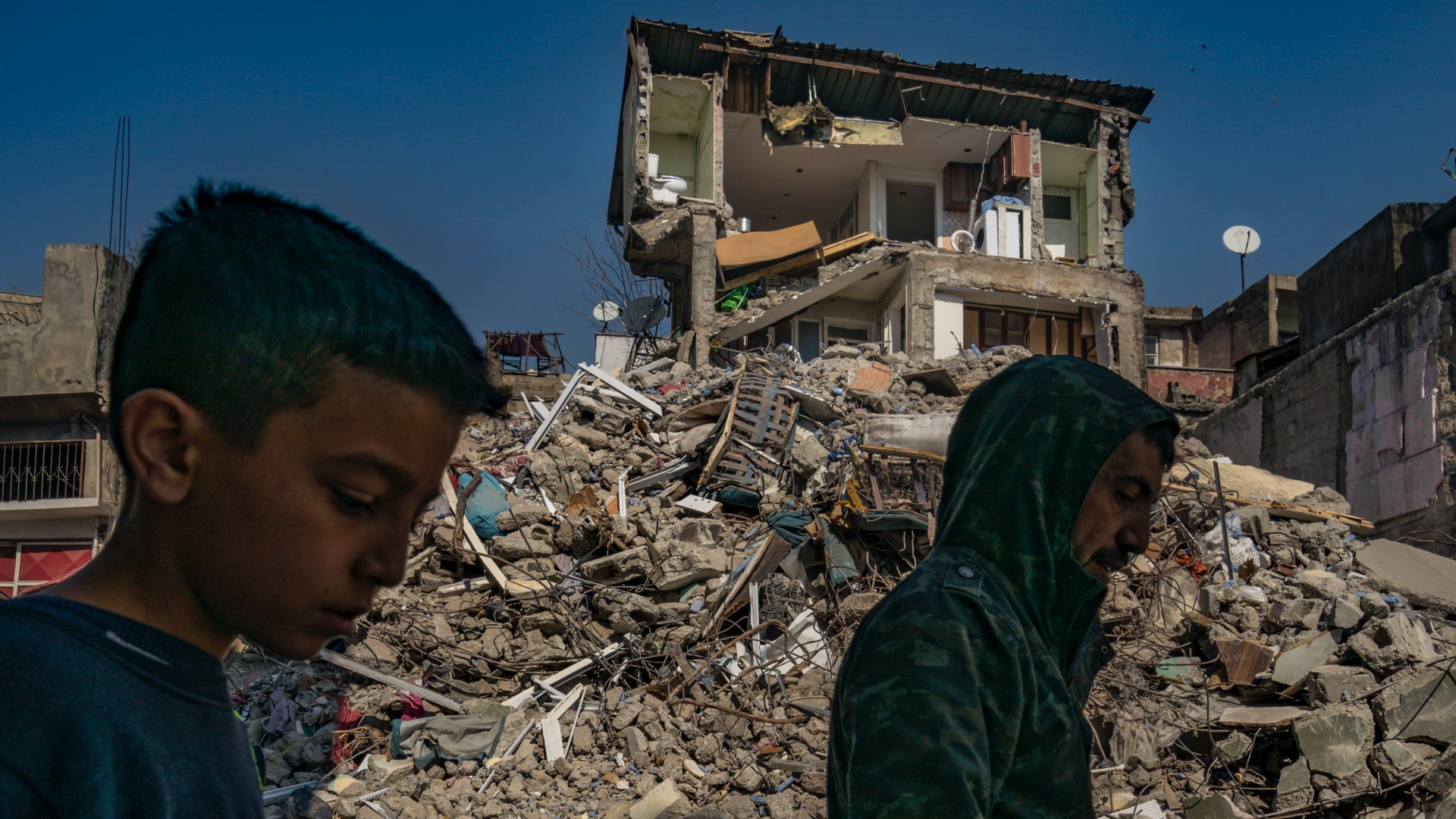Helyiek haladnak el Kahramanmarashban egy ház romjai mellett haladnak el, amelyet szinte kettészakított a heves földrengés Dél-Törökországban