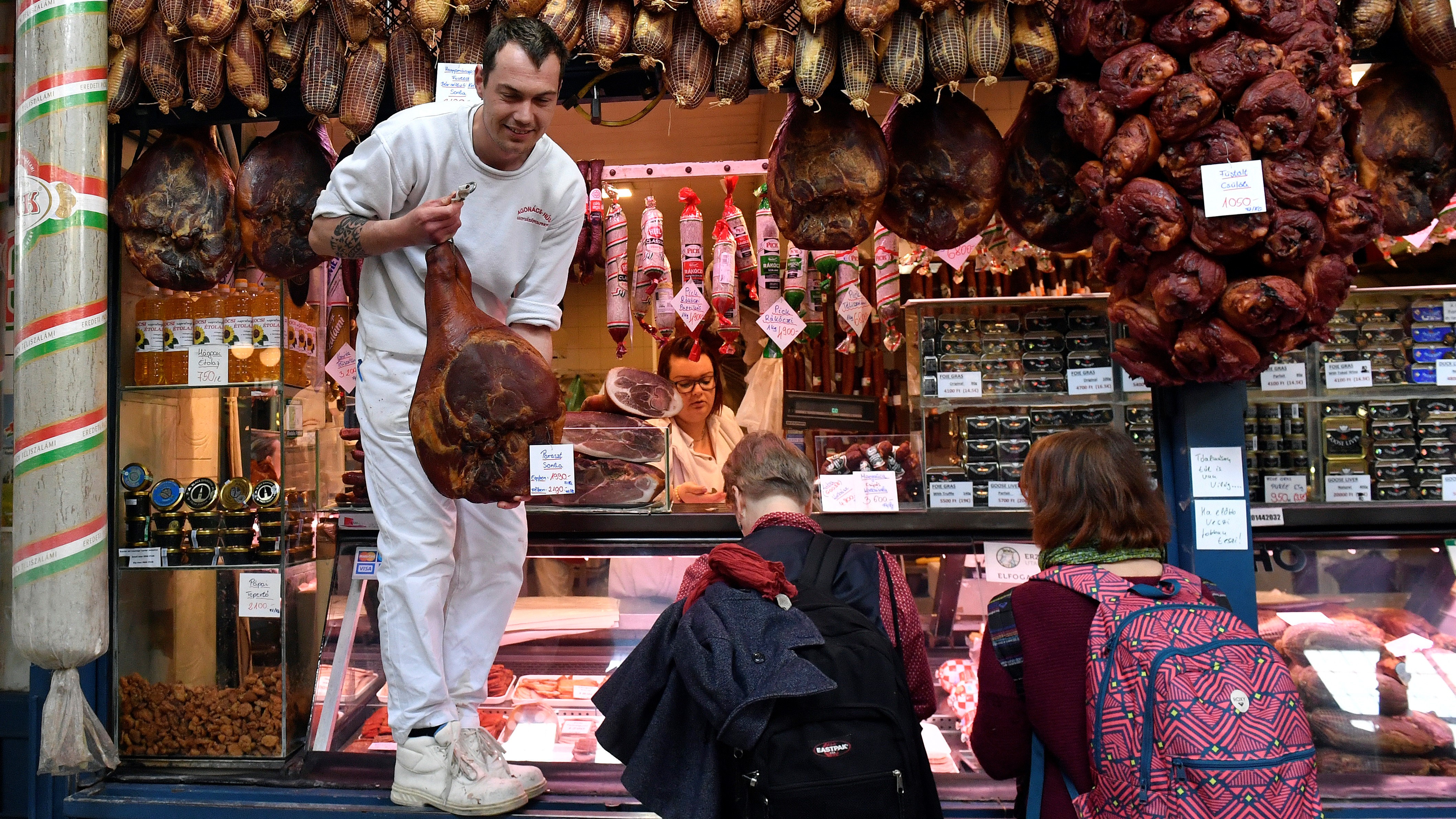 Húsvéti füstölt sonkát vásárolnak egy hús- és hentesárut árusító standnál a budapesti Fővám téri Központi Vásárcsarnokban