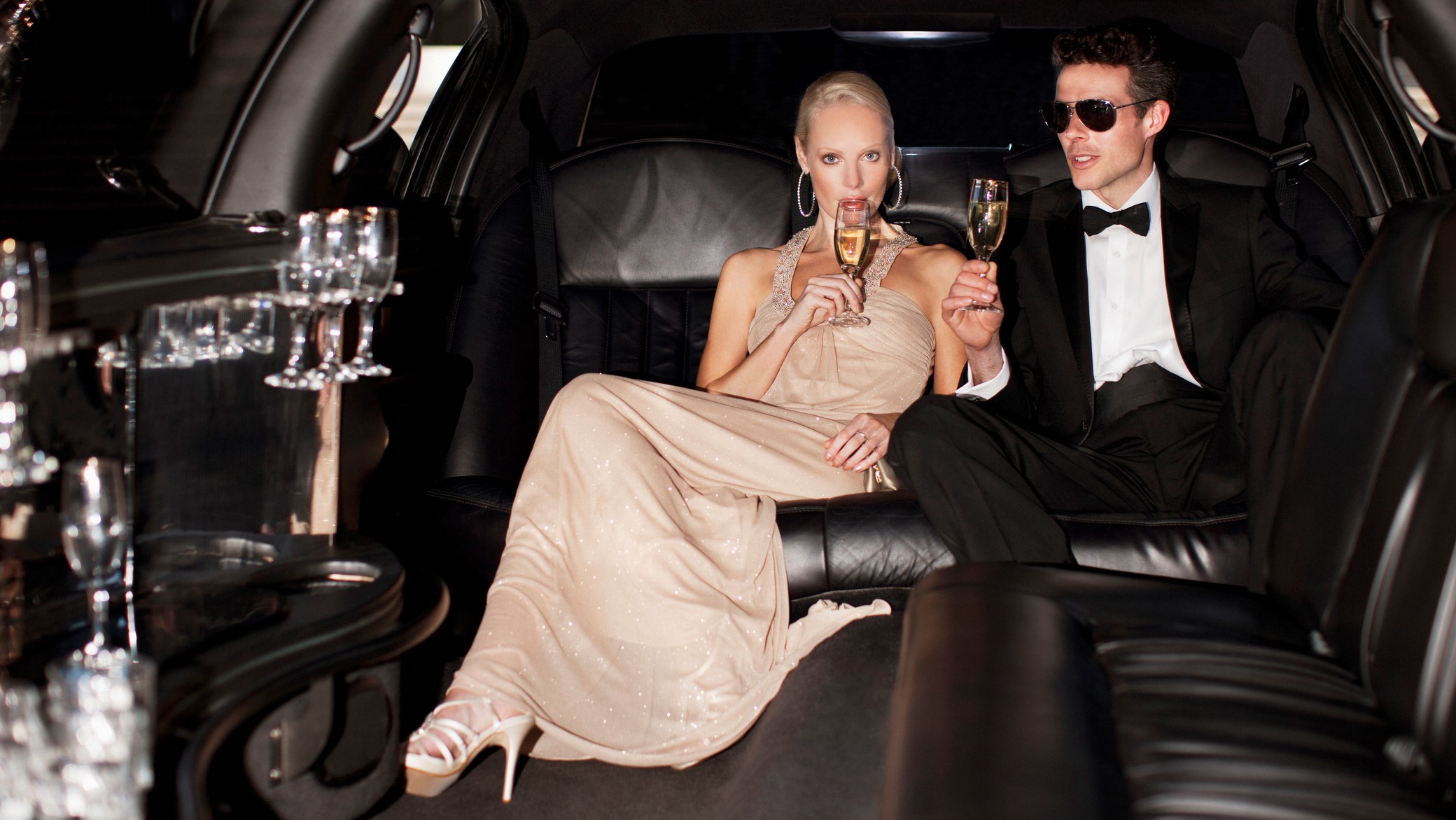 Egy gazdag, fiatal pár egy limuzinban pezsgőzik