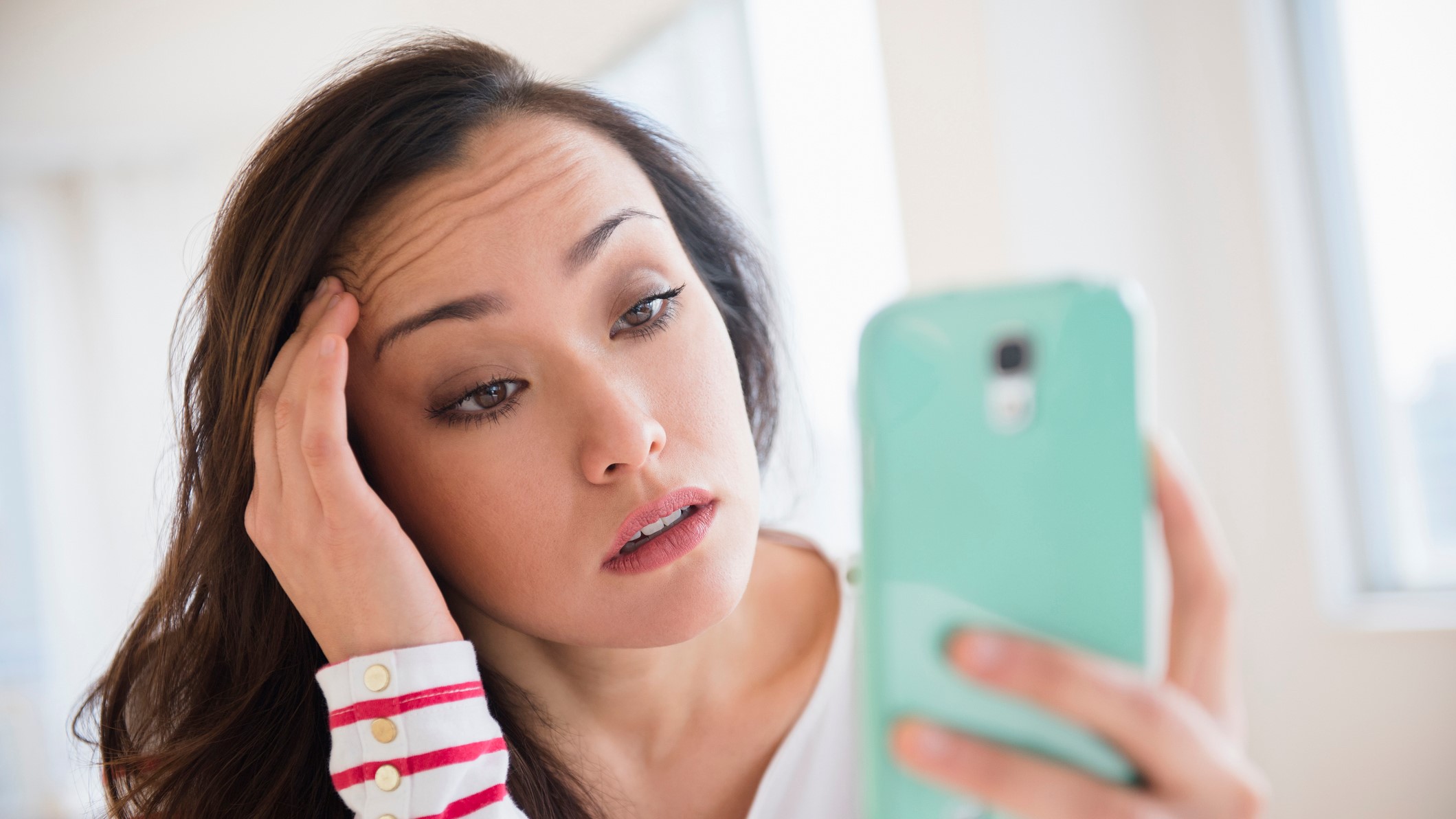 Nő stresszesen nézi a mobiltelefonját