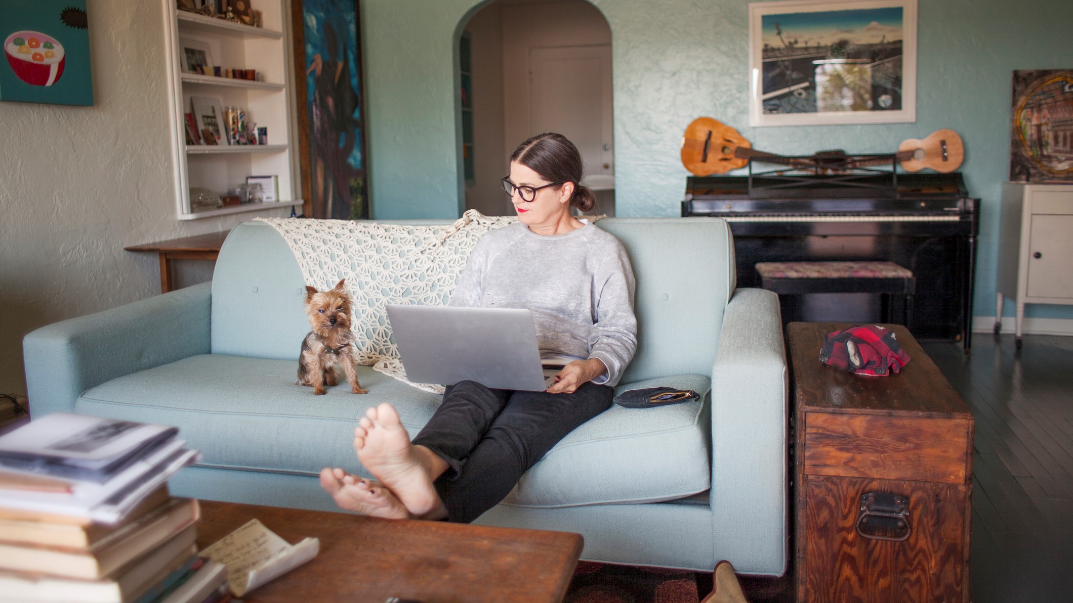 Egy nő laptopozik a kanapén kutyájával