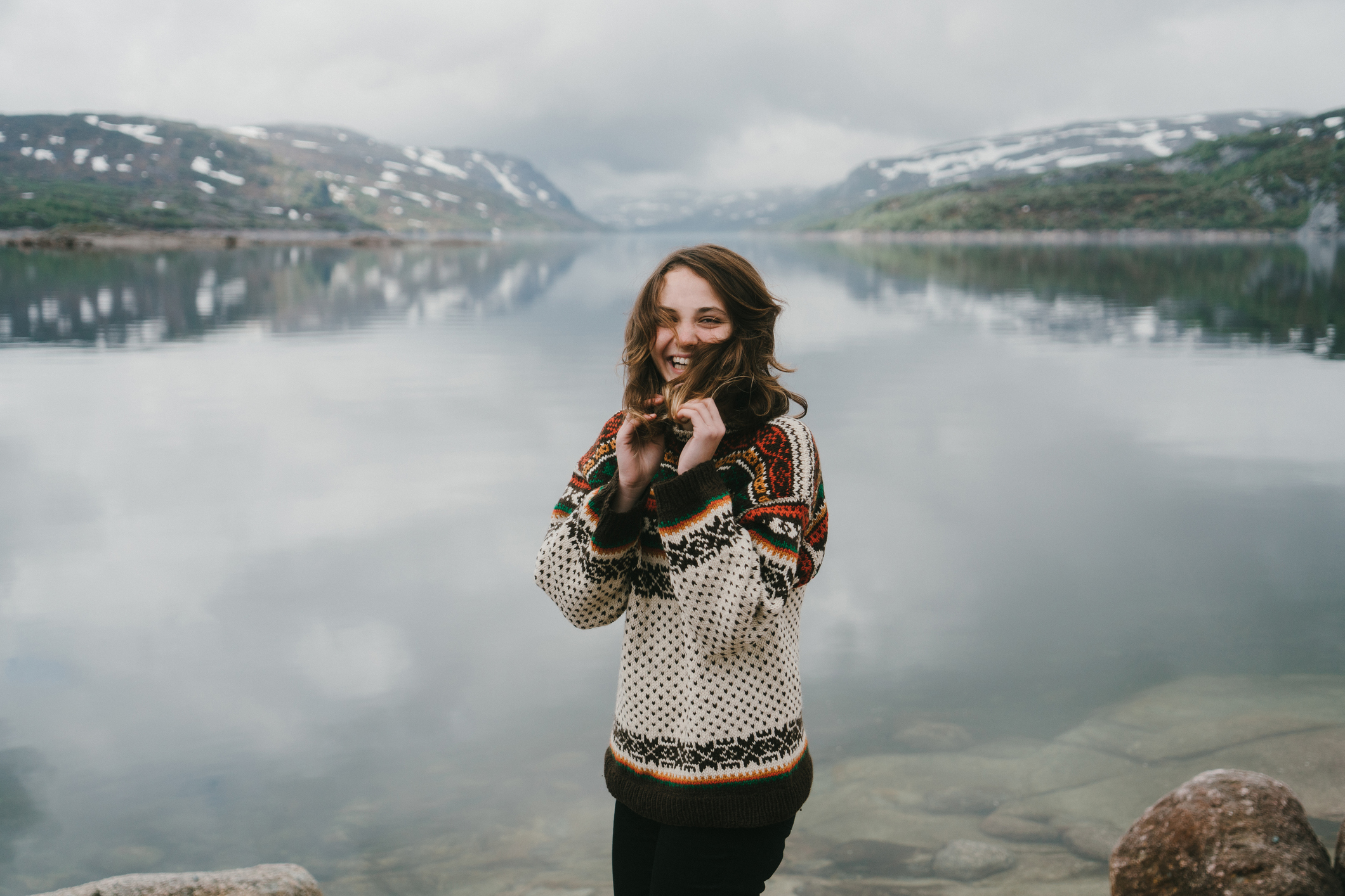 Egy nő pózol egy norvég tó előtt.