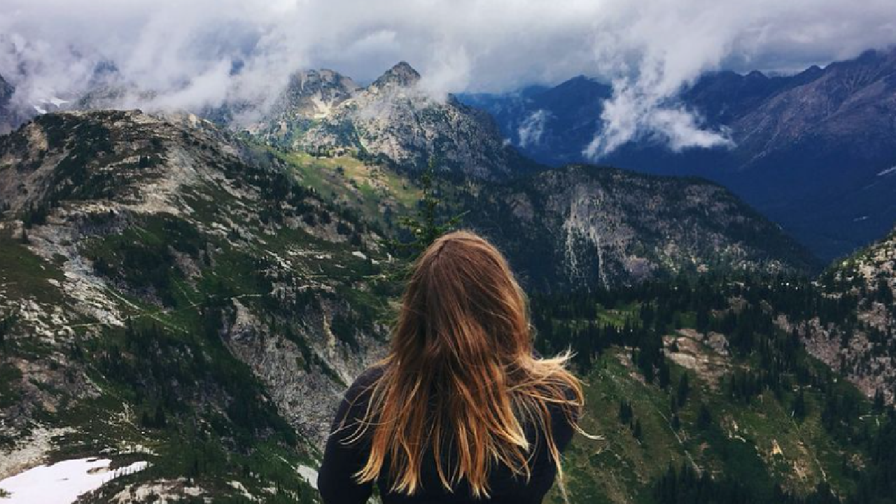 Egy nő áll hegyekkel szemben