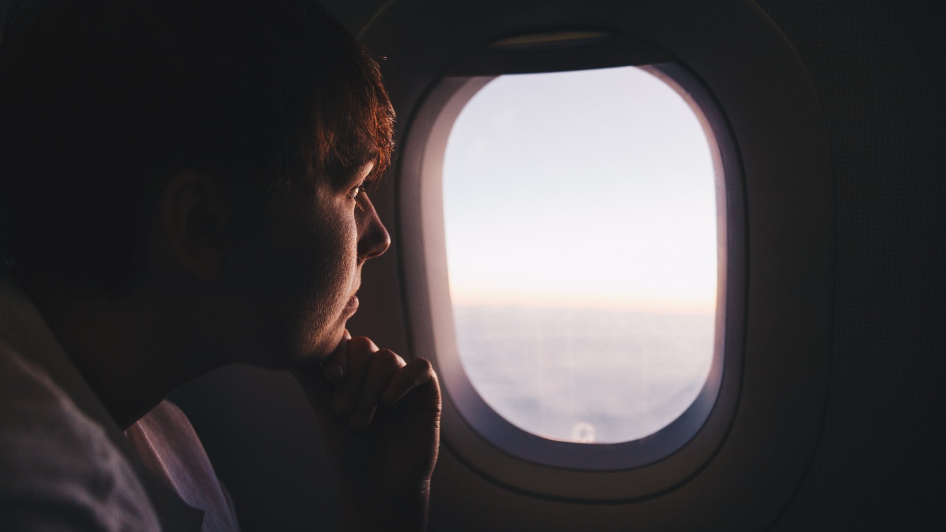 Egy fiatal fiú néz ki a repülő ablakán