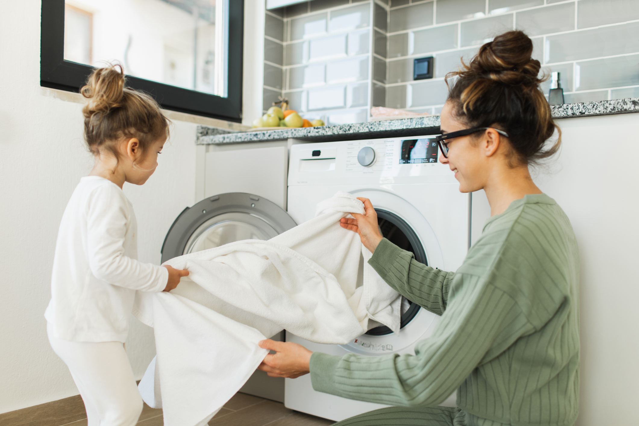 Édesanya és kislánya együtt szedi ki a frissen mosott ruhát a mosógépből
