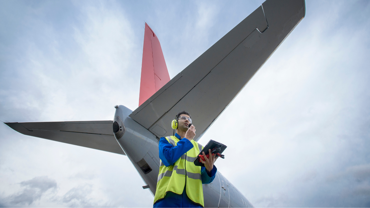 Egy légiforgalmi mérnök rádión beszél a kifutópályán lévő repülőgép közelében