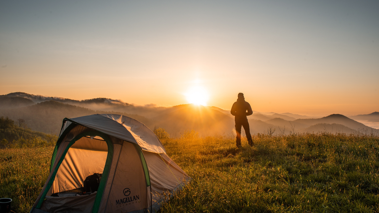 Egy férfi sátrazás közben a naplementét nézni