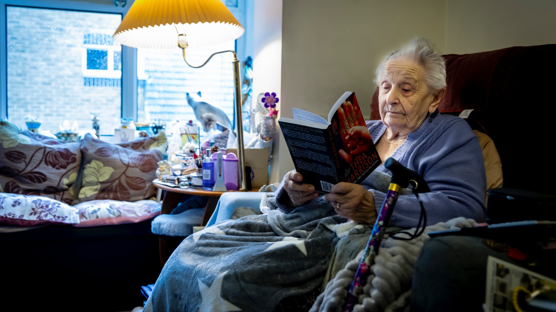 Egy nyugdíjas nő a fotelben ülve olvas