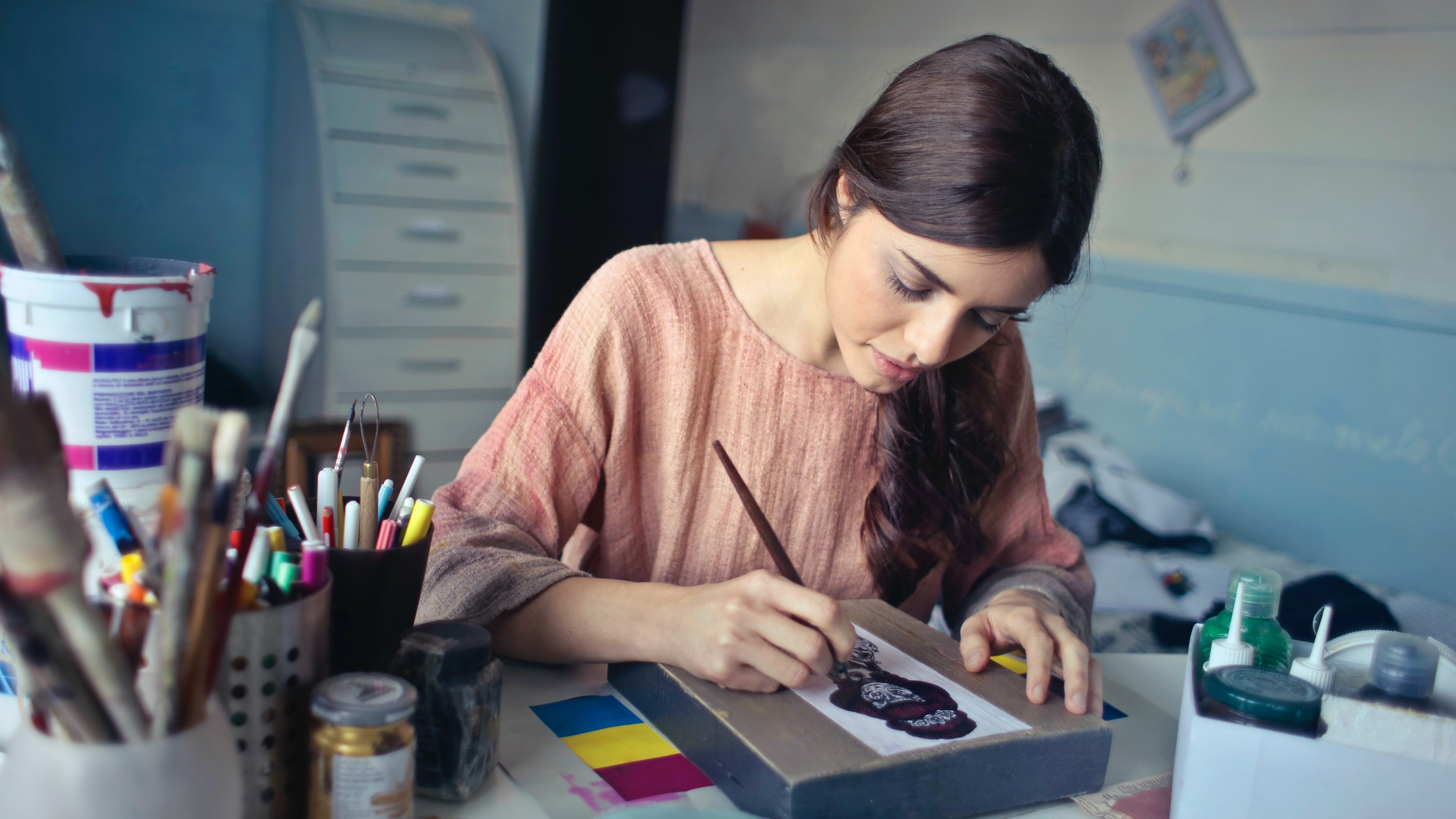 Fiatal nő rajzol egy asztalnál