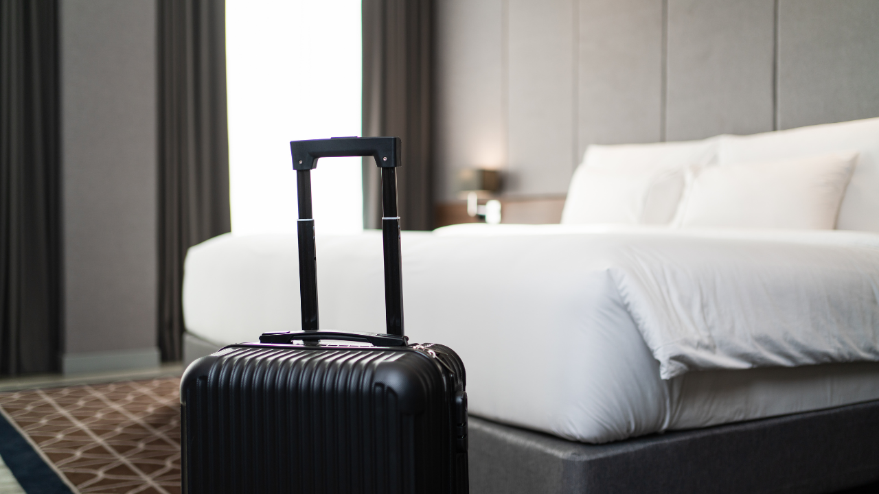 Egy bőrönd a hotelszobában lévő ágy előtt