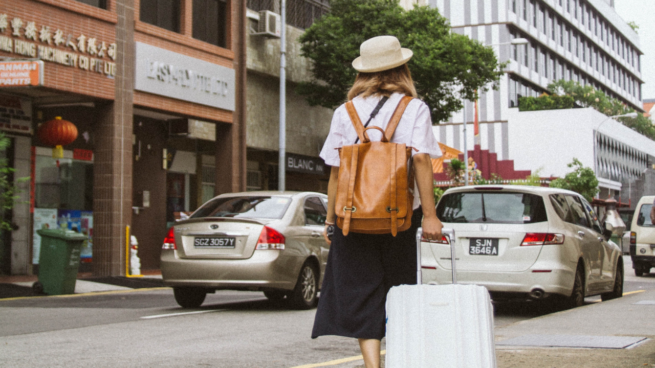 Egy nő bőrönddel utazik a városban