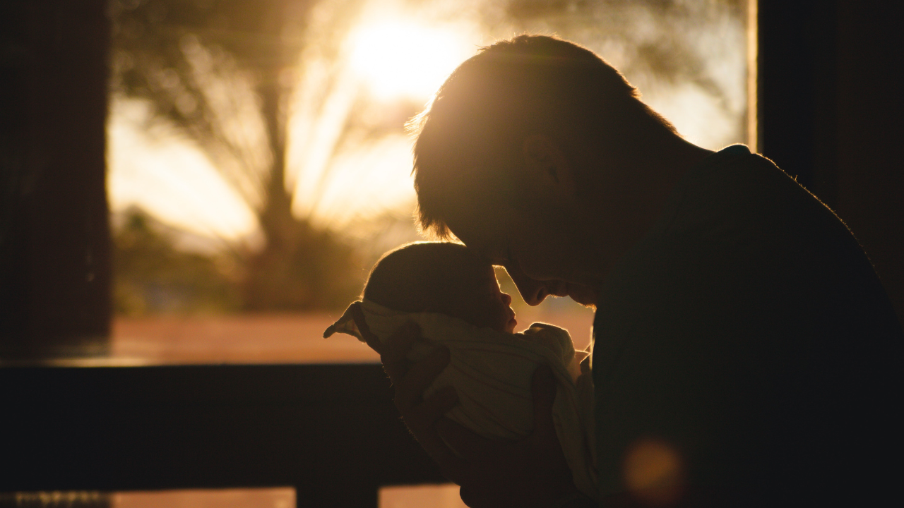 Egy édesapa az újszülött kisbabáját tartja a kezében