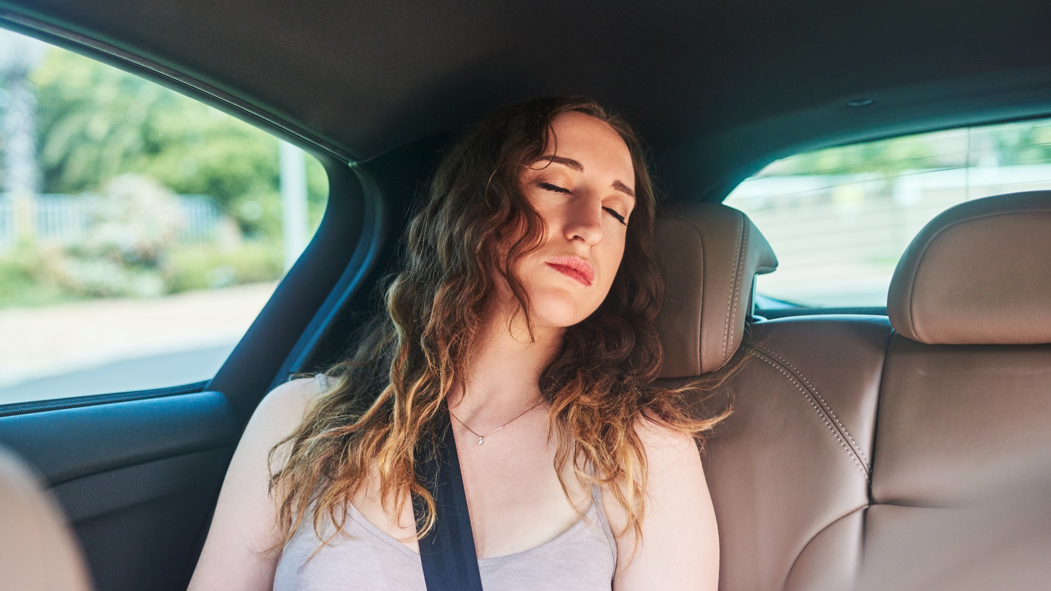 Nő alszik egy autó hátsóülésén