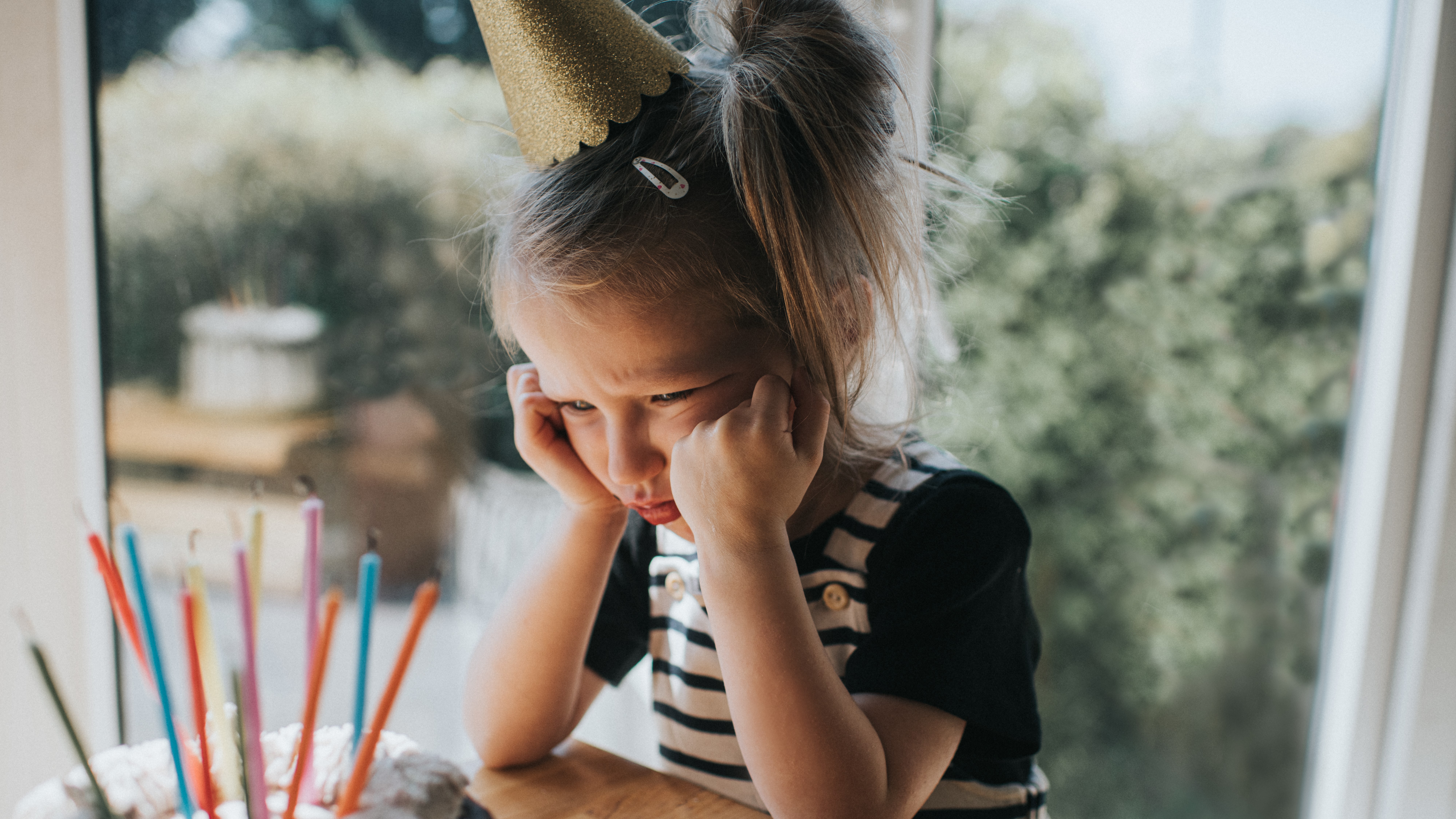 Szomorú kislány születésnapi tortával