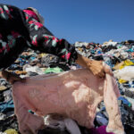 Egy nő keresgél egy szeméttelepen egy hegynyi használt ruha között az Atacama-sivatagban.
