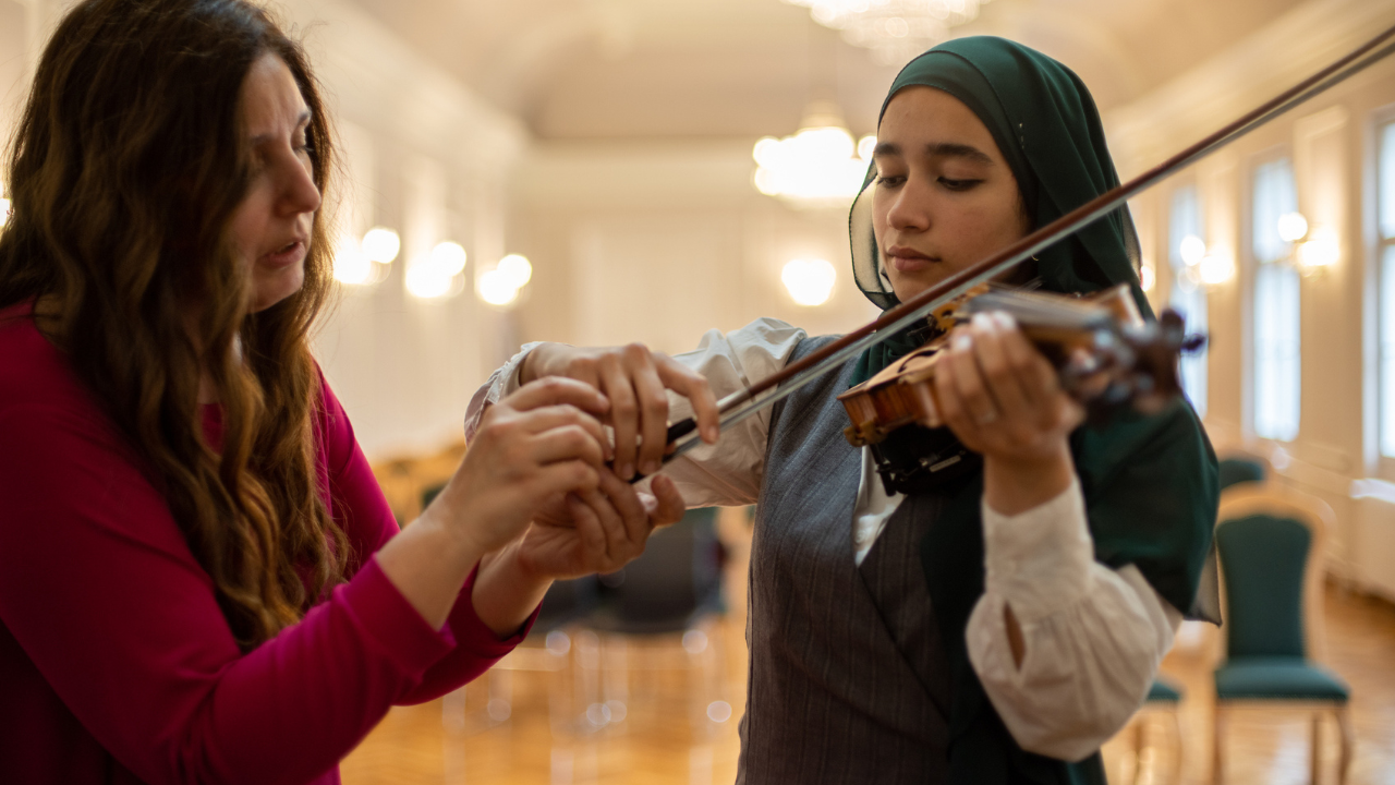 Hegedülni tanítja a zenetanár az egyik diákját