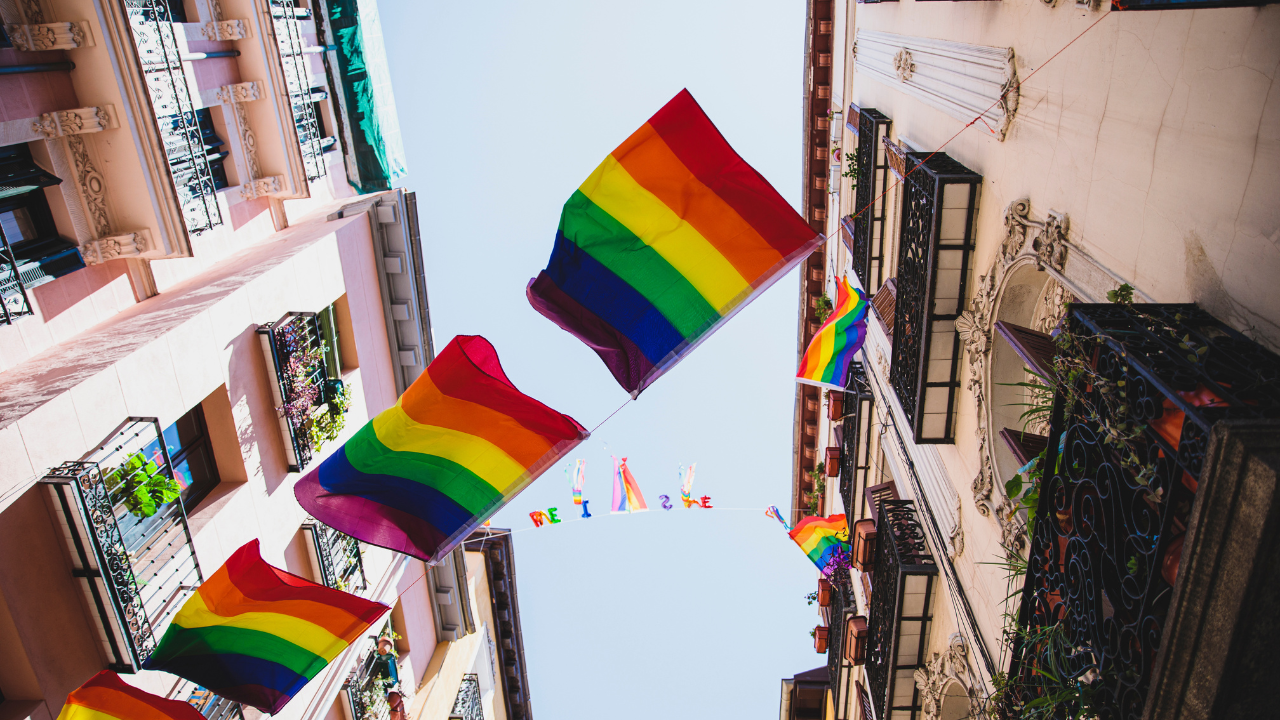 A Pride-ot szimbolizáló színes zászló van kifeszítve két ház között.