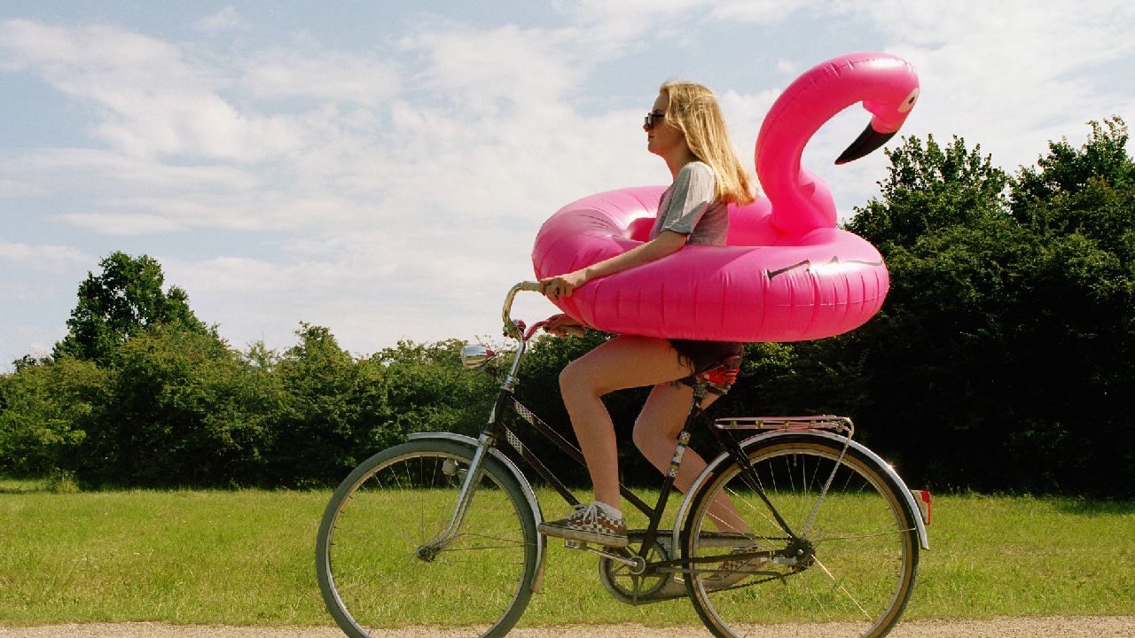 Nő biciklin, flamingó úszógumival