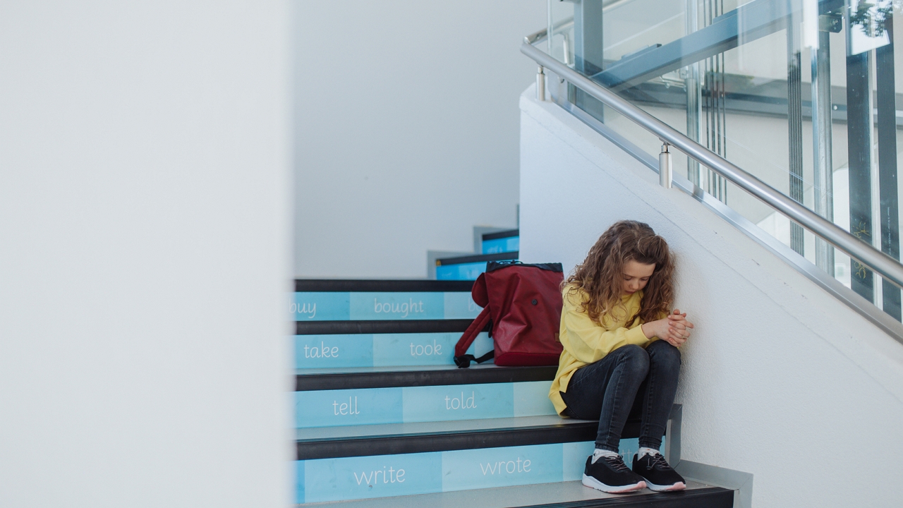 szomorú kislány az iskola lépcsőjén