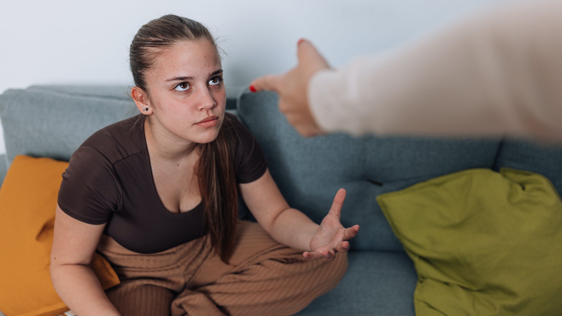 Egy tinédzser lány vitatkozik az anyjával a kanapén ülve