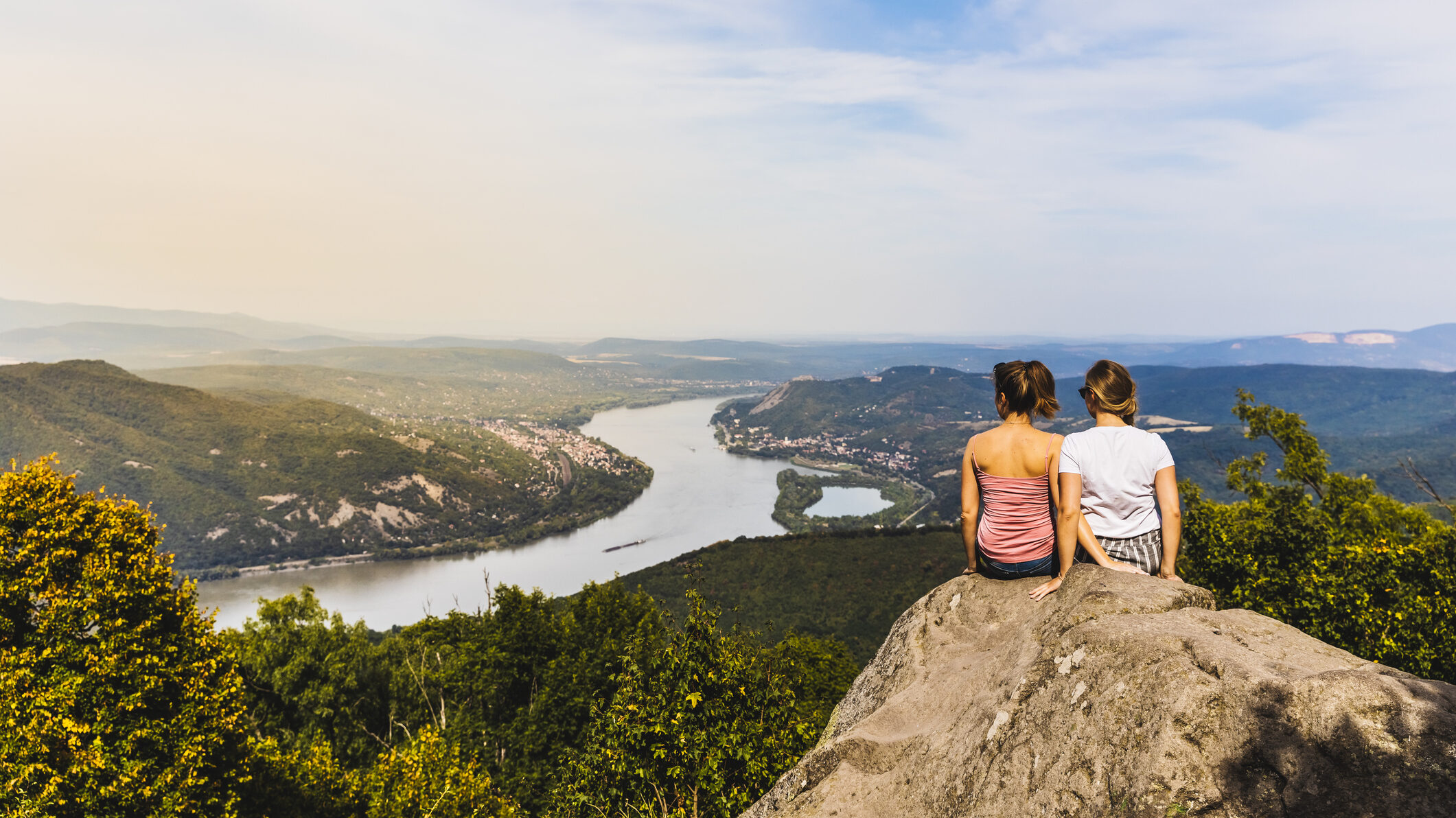 Két barátnő ül egy sziklán a Budai-hegységben. és letekint a Dunára.