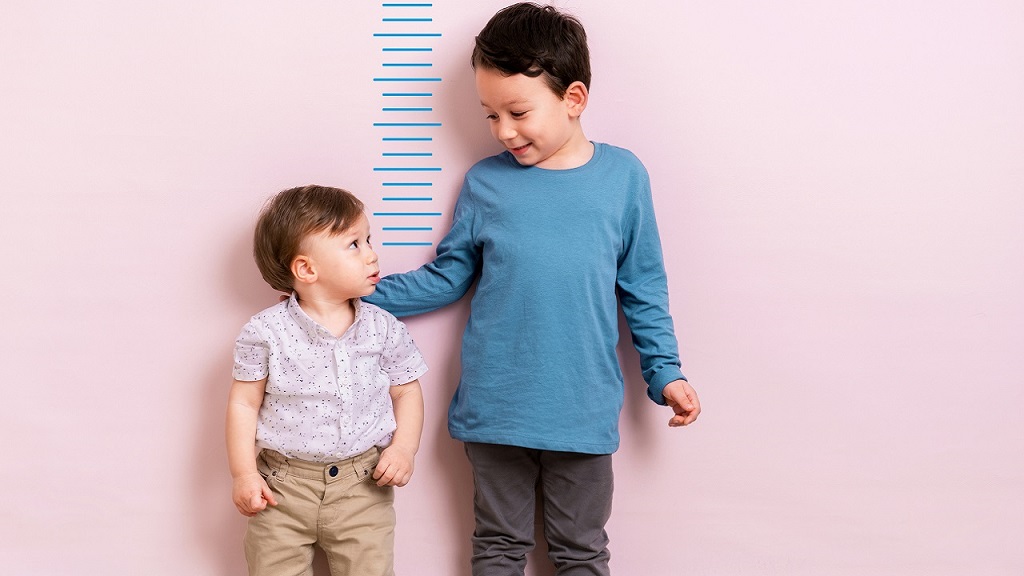 Két kisfiú áll a rózsaszín fal előtt