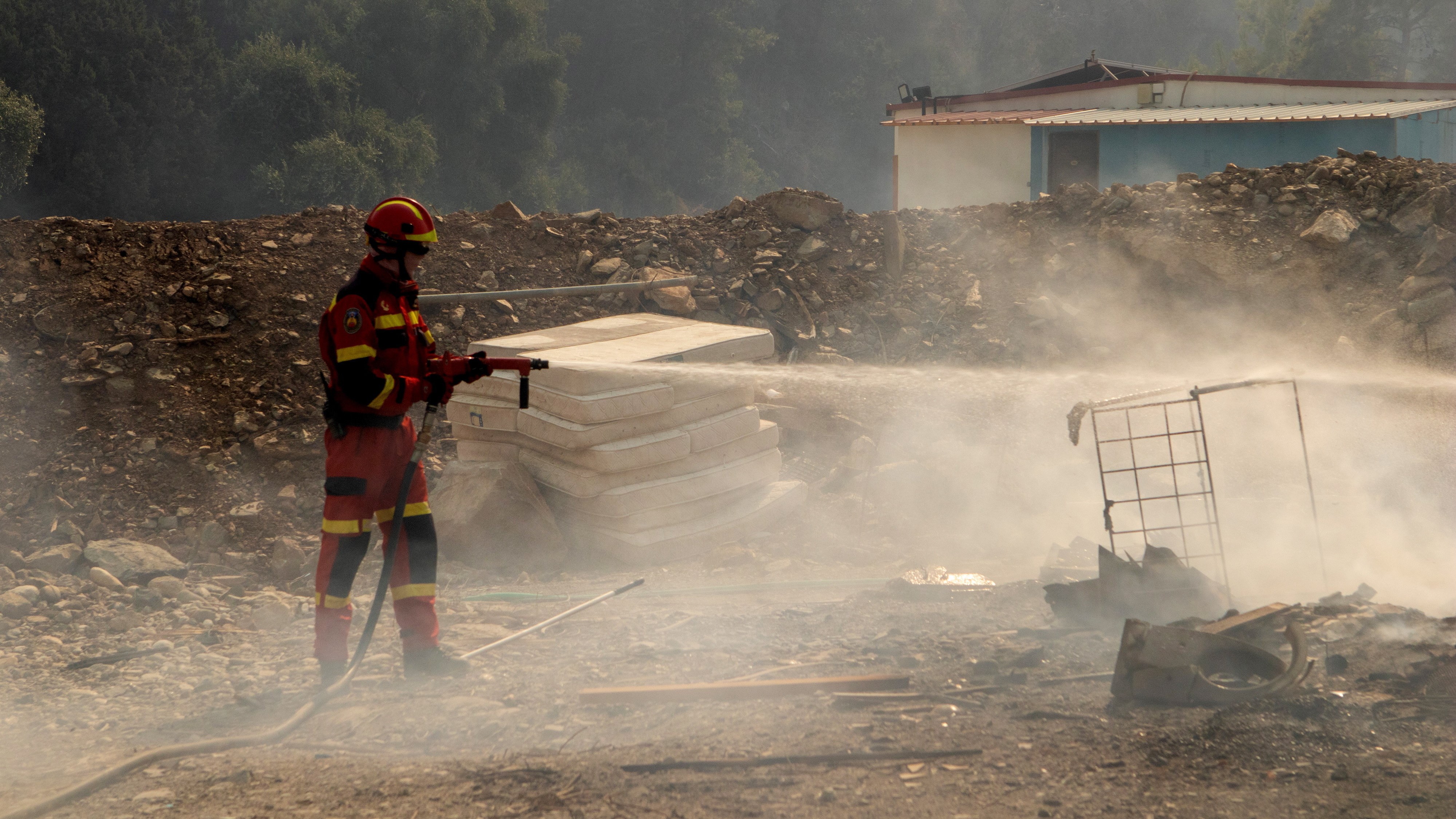 Bozóttűz lángjait locsolja egy tűzoltó a Rodosz szigetén