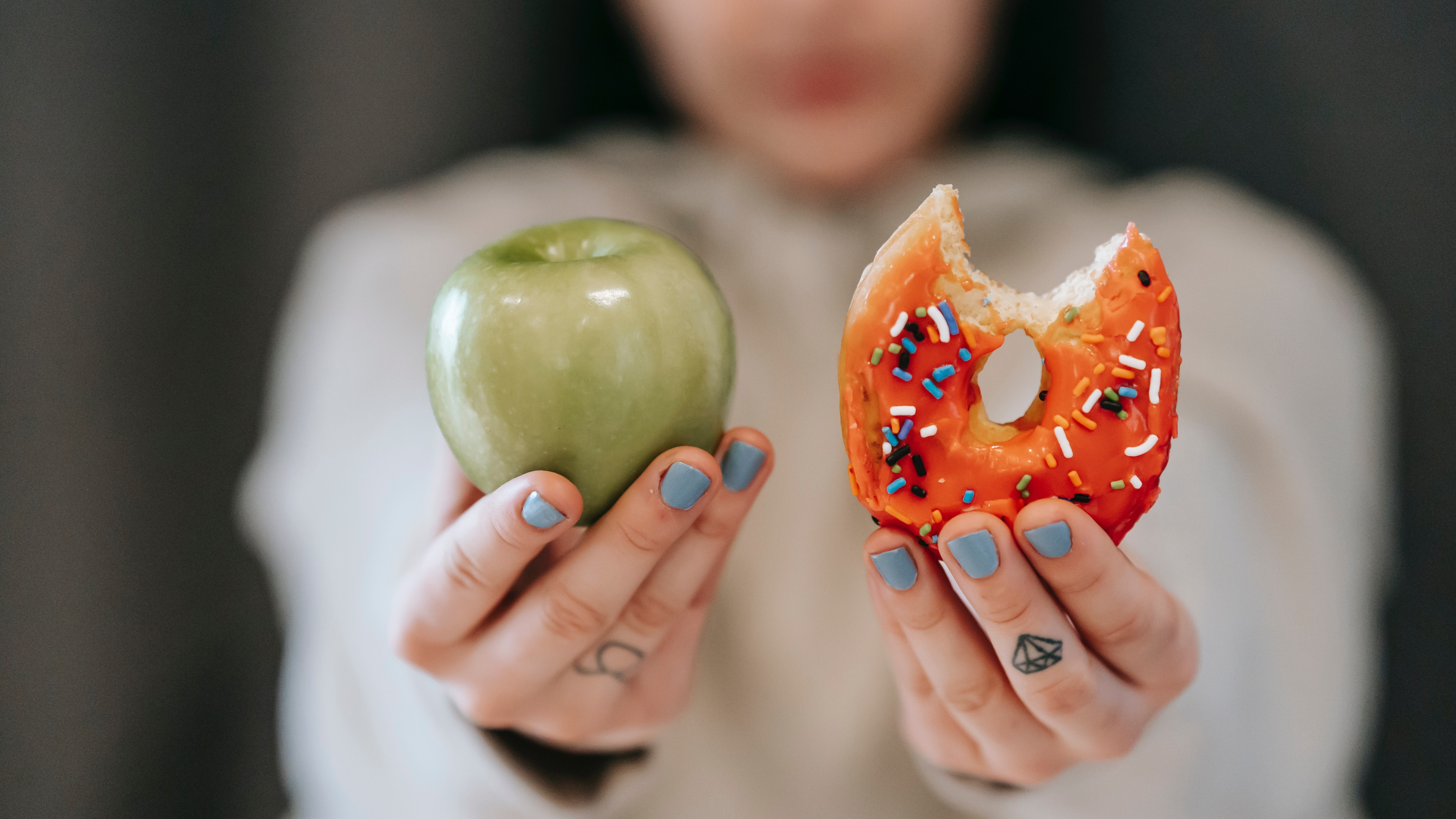 Fiatal nő almát és fánkot tart a kezében